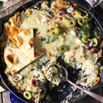 Mediterranean Spinach Artichoke Dip is baked to creamy, cheesy perfection and served with toasted pita bread. Bursting with flavor from spinach, artichokes, olives, and feta cheese, this easy dip is a party favorite!