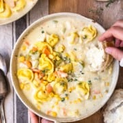 dipping bread in creamy chicken and cheese tortellini soup