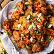 bite size fried chicken pieces on a serving dish with fried onion and peppers