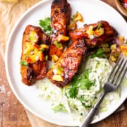 grilled boneless pork ribs on a plate with coleslaw and peach pico de gallo next to a glass of beer