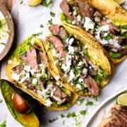 carne asada flank steak inside tortilla shells with garlic lime crema