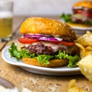 elk burger on a plate with chips and a beer