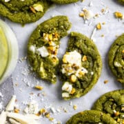 white chocolate pistachio matcha cookie broke in half laying on parchment paper with more cookies