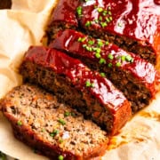 Meatloaf with three slices next to a pinch bowl of salt and a glass of red wine.