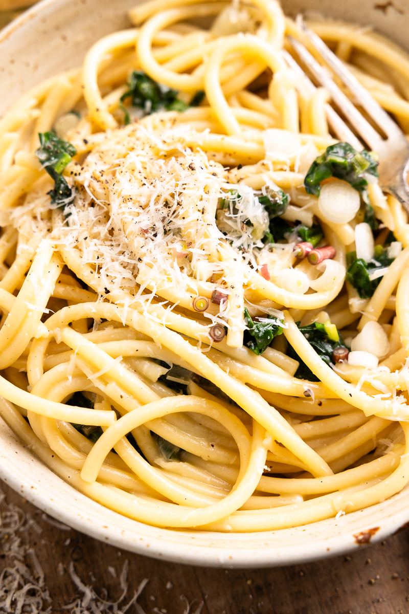 close up of ramp pasta in a bowl and garnished with parmesan and black pepper