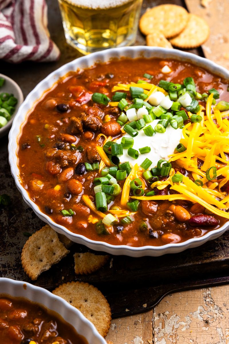 bowl of venison chili topped with cheese, green onions and sour cream